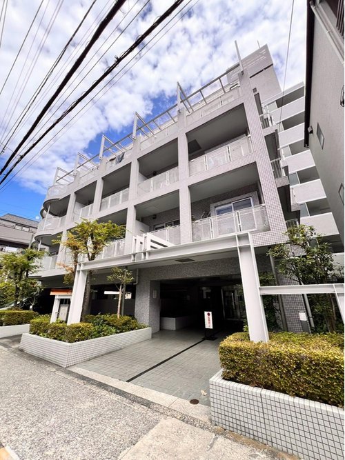 白を基調とした落ち着きのある色味と緑豊かな植栽が調和した外観です。